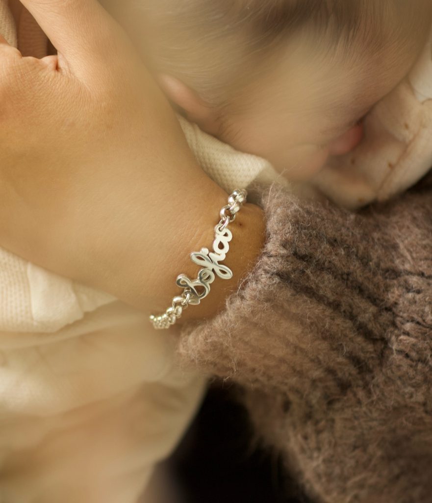 bracelet prénom découpé en argent, bras qui tient un bébé